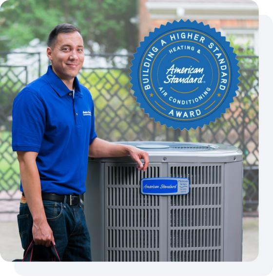 An American Standard Heating &amp; Air Conditioning dealer standing by an outdoor HVAC unit.