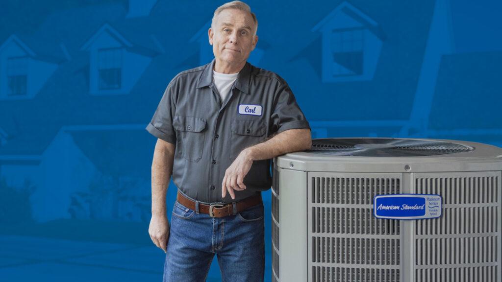 An hvac specialist is standing next to an American Standard unit.