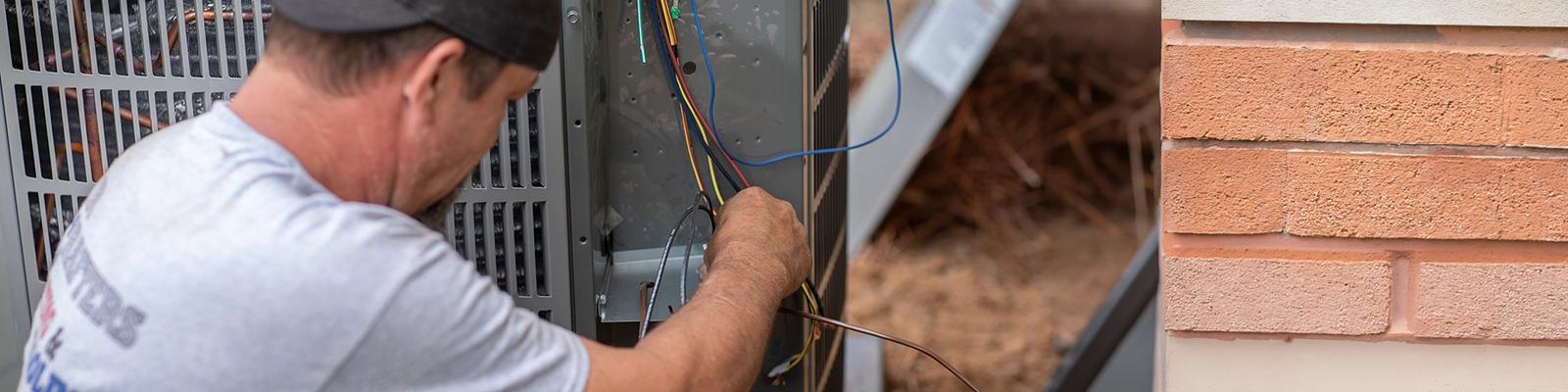 HVAC Technician Working on an Outdoor AC Unit.