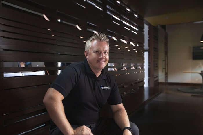 Reed Barton of Premier Heating + Air based out of Denver, CO, in front of a wooden slat wall.