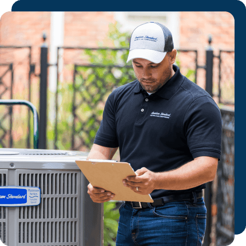 HVAC technician looking at a clipboard near an outdoor air conditioner.