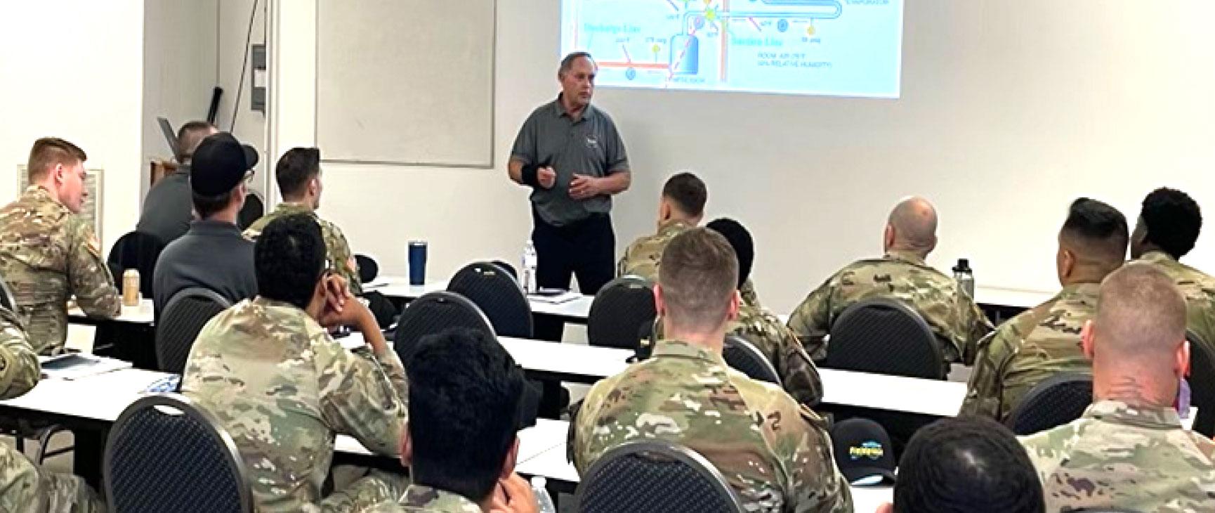 A teacher is in a classroom lecturing a class of military students.