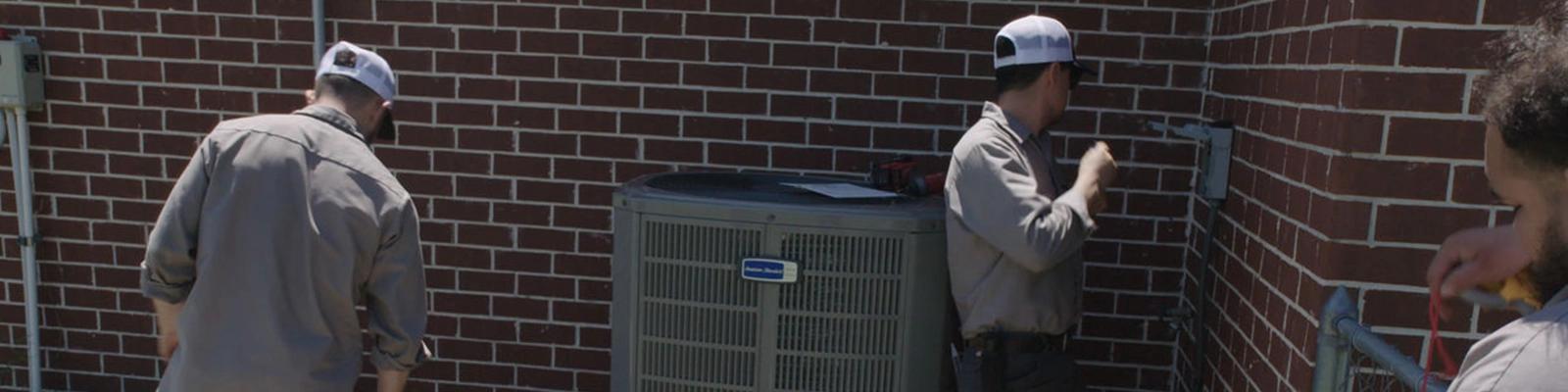 HVAC Technician and Homeowners by a New AC Installation.