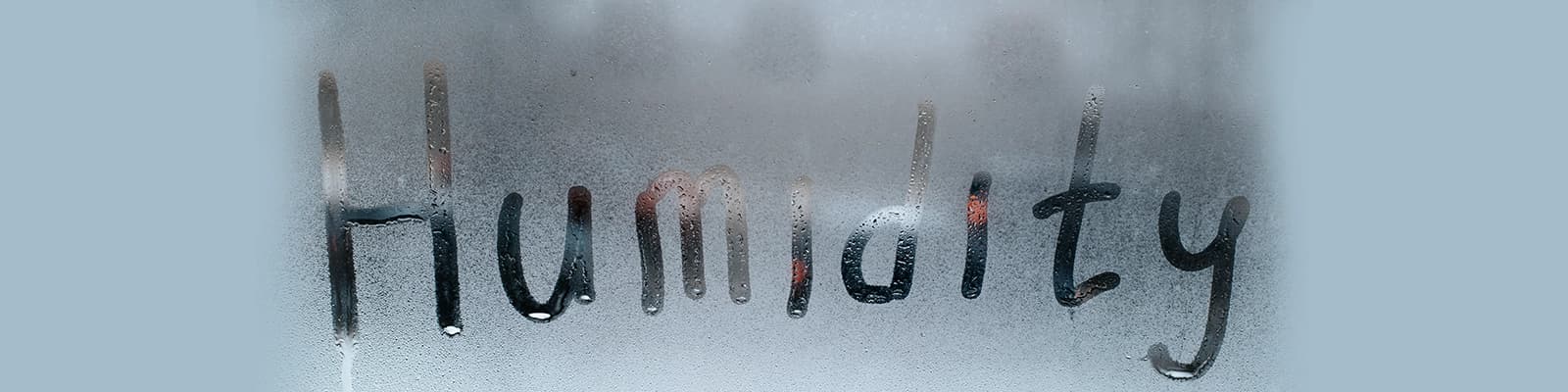 The Word Humidity Written on a Window Heavy with Condensation.
